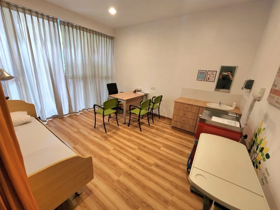 Clinic room at Eden on the Park with an examination bed, desk, and sink