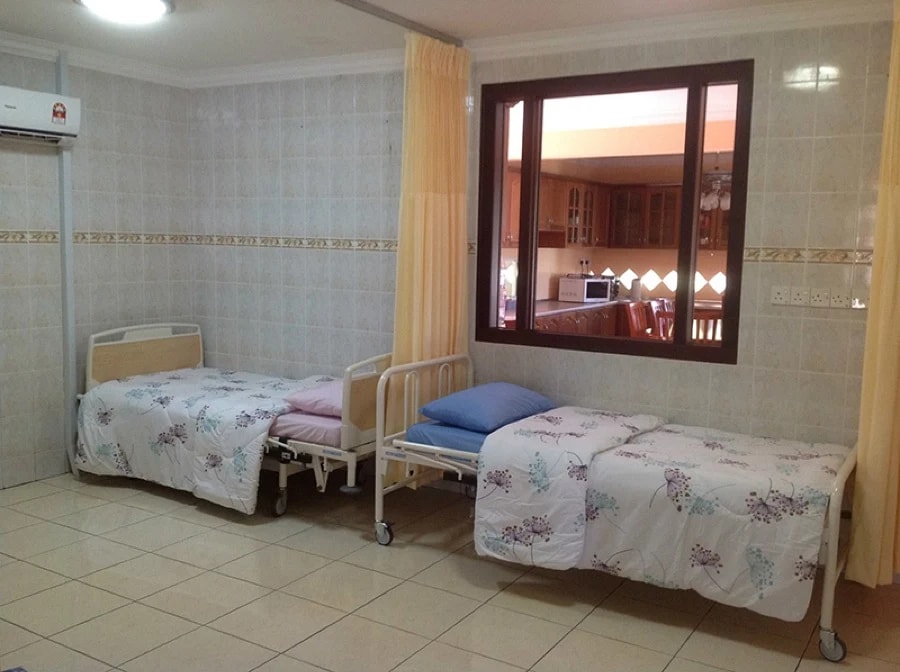 Room at Kenneth Care Home with three adjustable care beds and a window into the kitchen