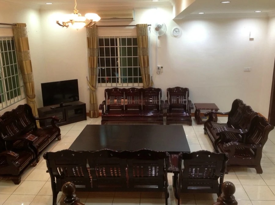 Sitting room at Kenneth Care Home with wooden sofa sets around a low table and a television