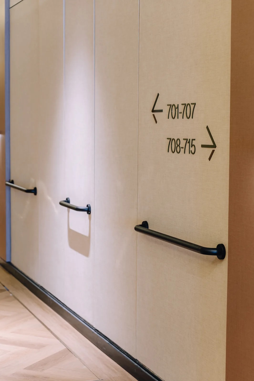 Care Collective corridor with grab rails along the wall and wayfinding signs