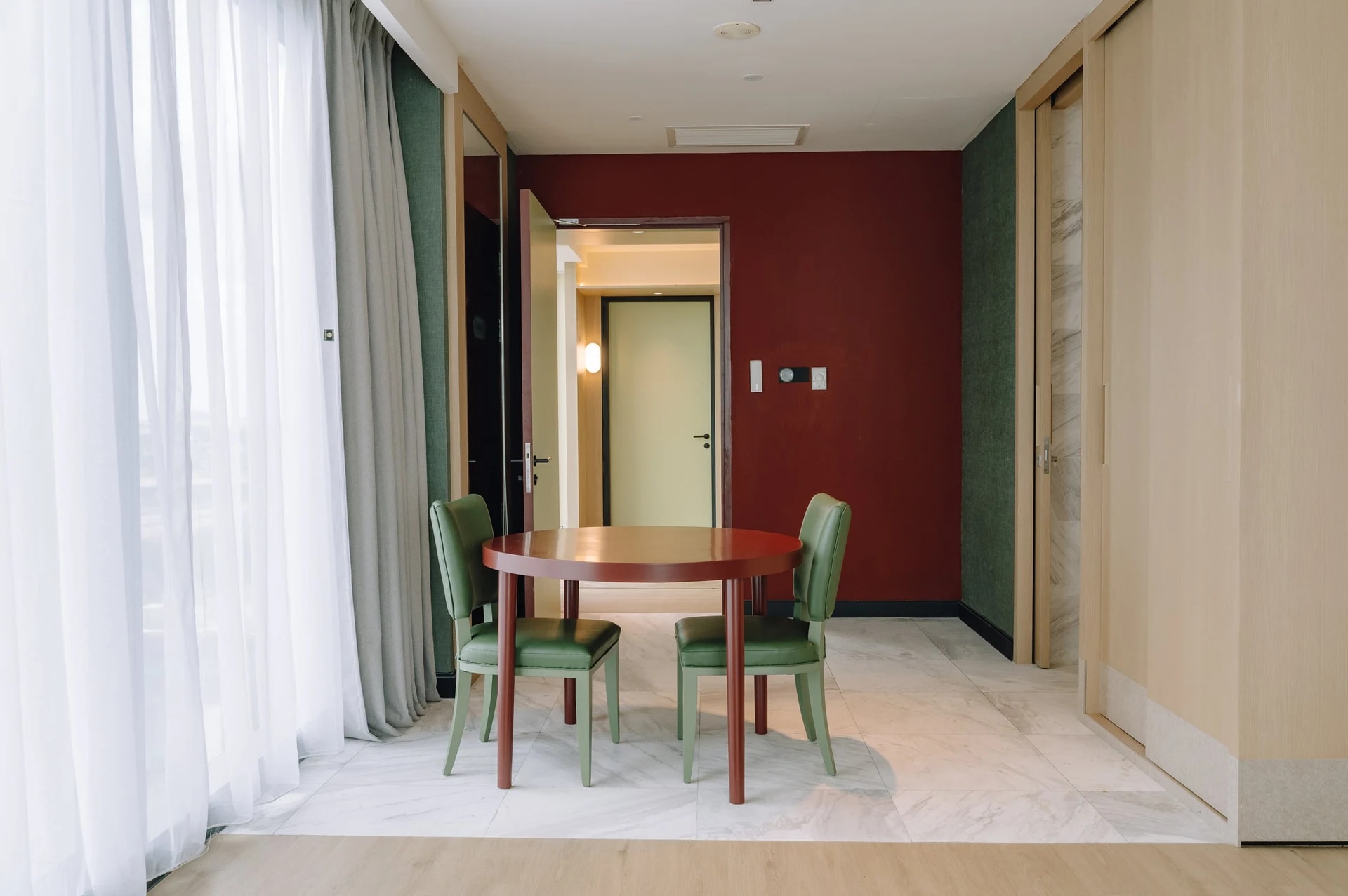 Dining nook at Care Collective with green chairs and a burgundy wall