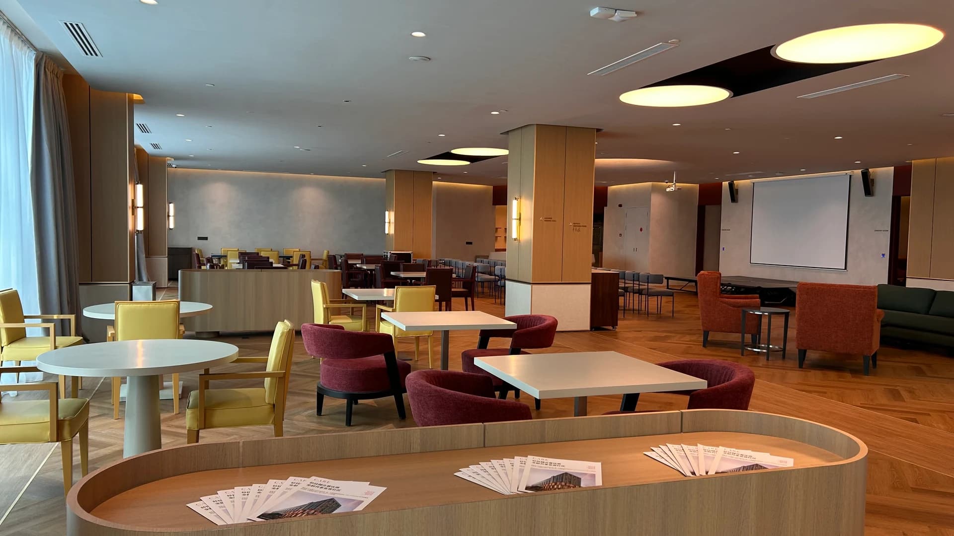 The Clubhouse lounge with round tables, armchairs and a screen