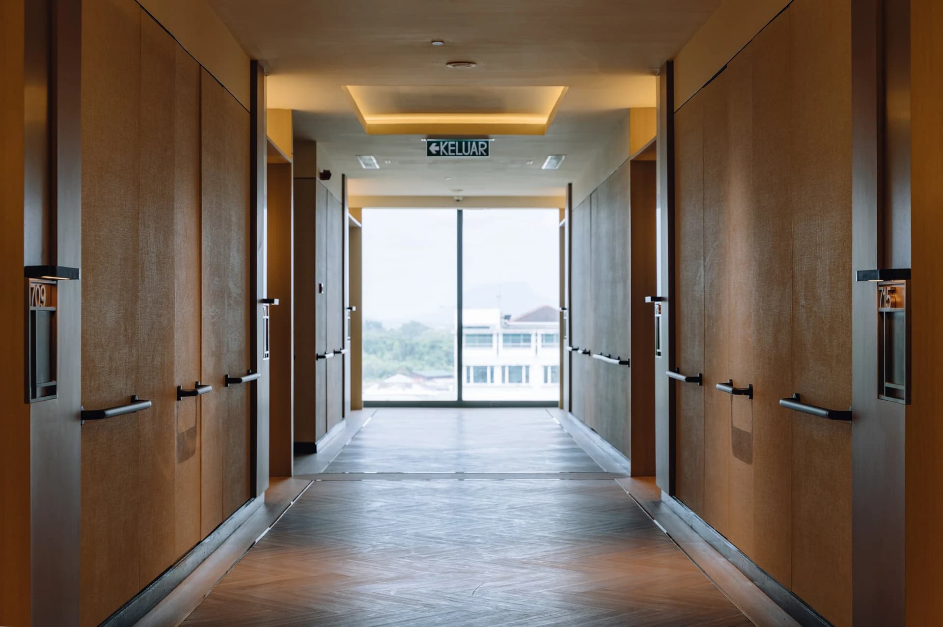 A Care Collective corridor with grab rails along both walls and a window at the far end