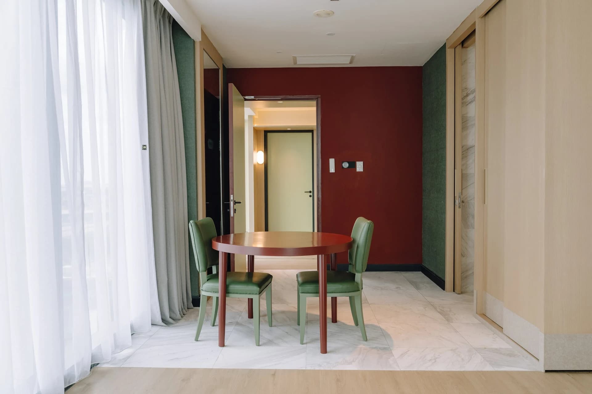 A dining nook with a round table and a burgundy accent wall