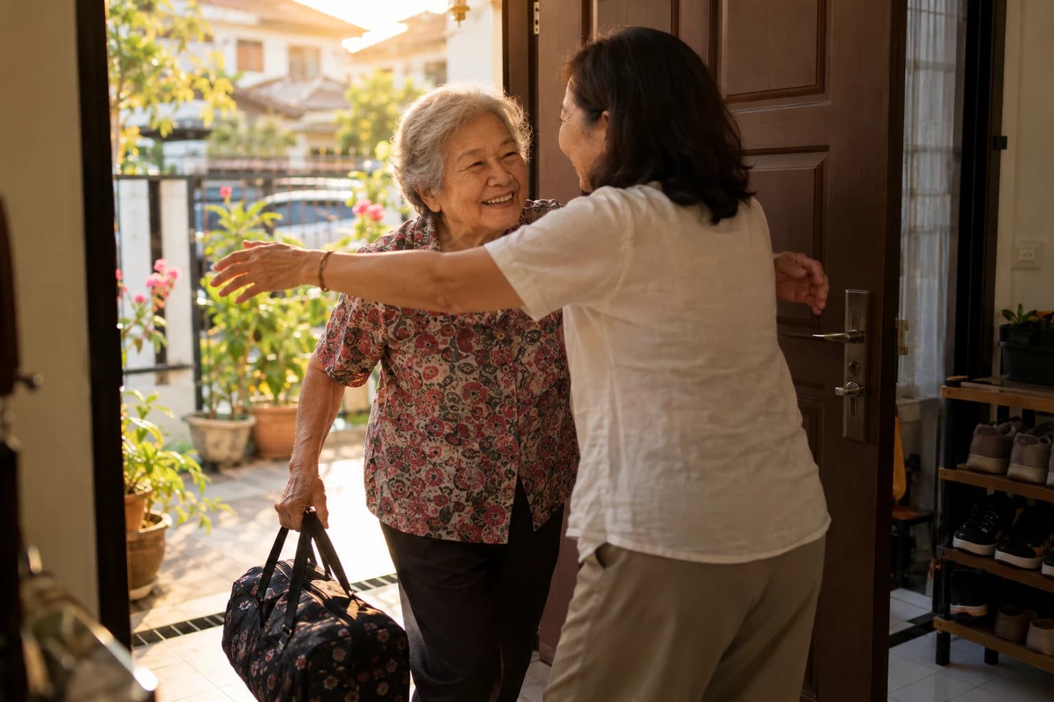 At the front door, a woman hugs her mother, who has just come home carrying a small travel bag