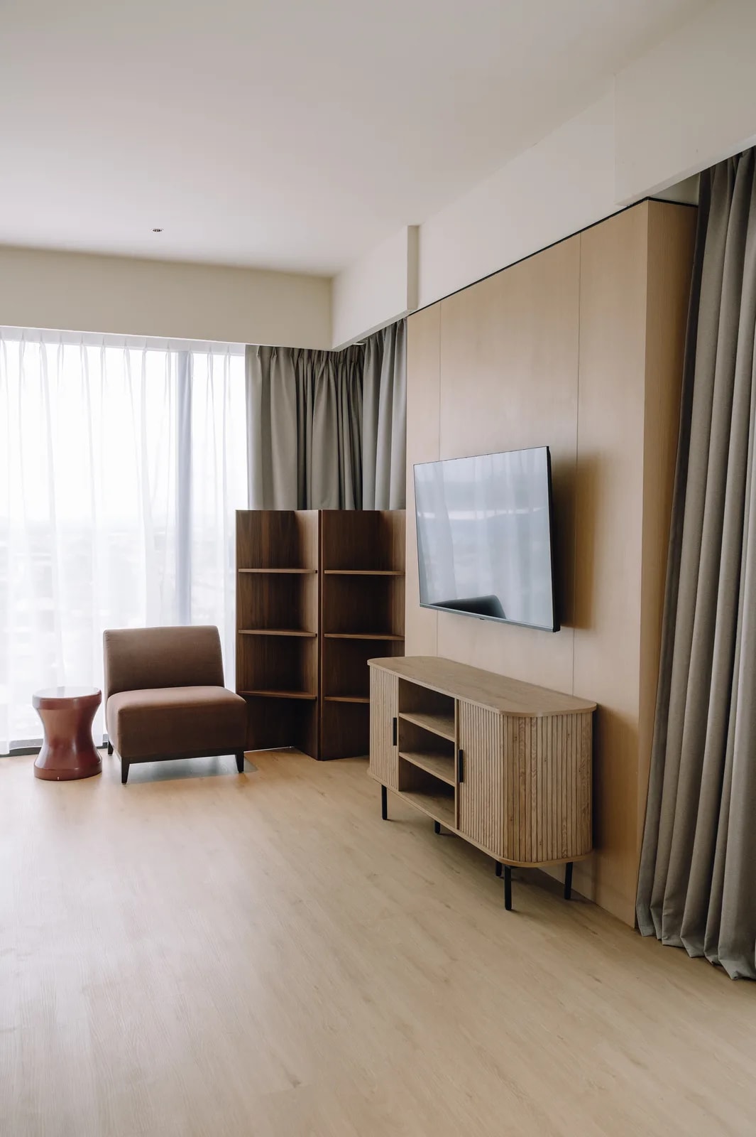A lounge area in a Care Collective suite with an armchair, shelves and television
